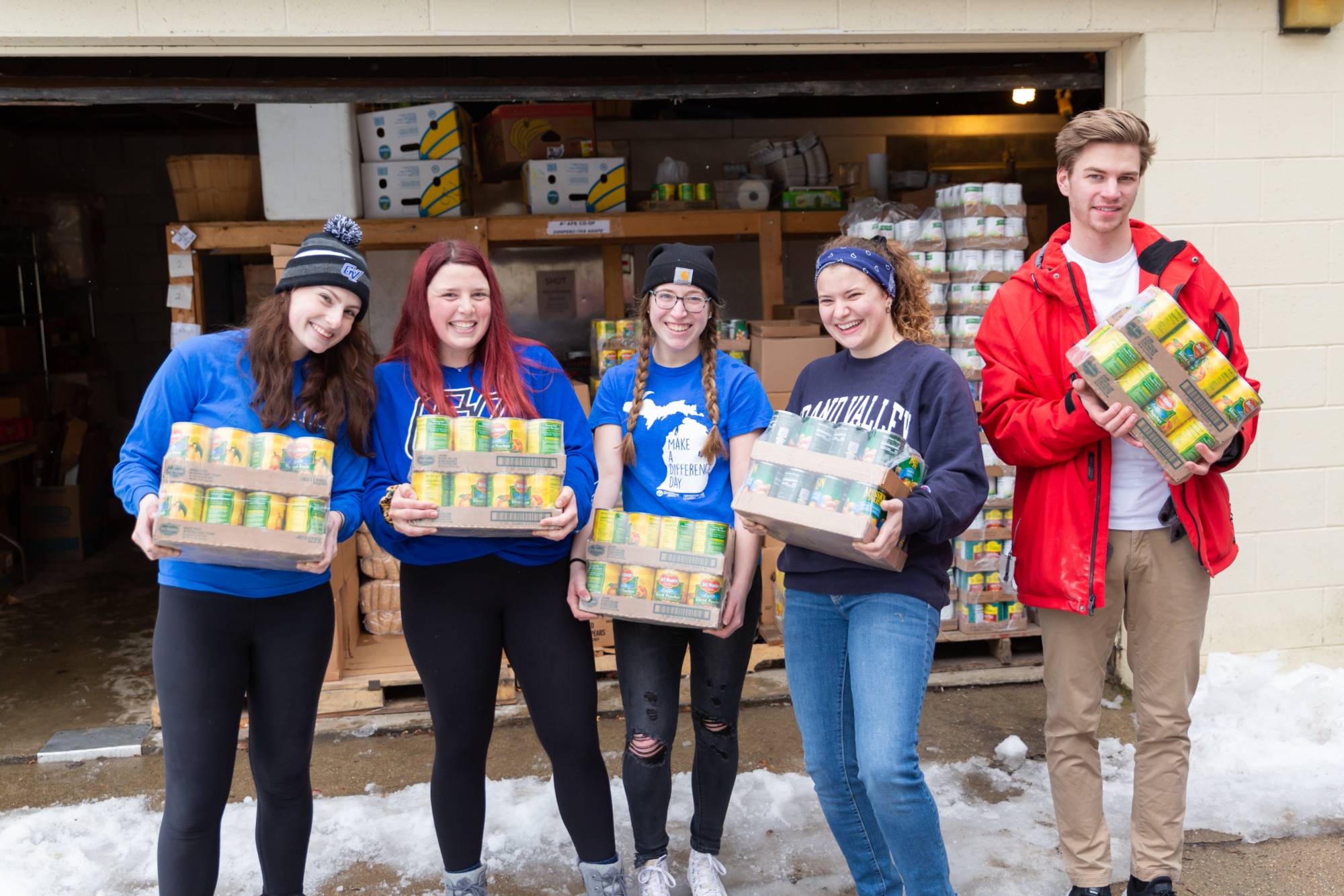 Students smiling for the camera and holding canned goods and assorted food items
